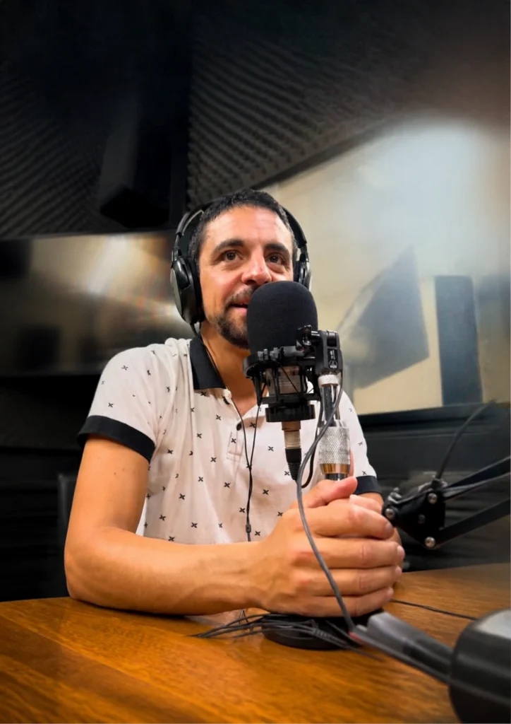 Mauricio Irigoyen con auriculares, hablando frente al micrófono en un estudio de grabación